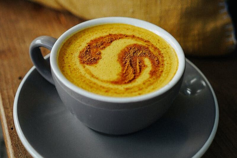 Warm turmeric latte with cinnamon froth art, served in a cozy indoor setting.