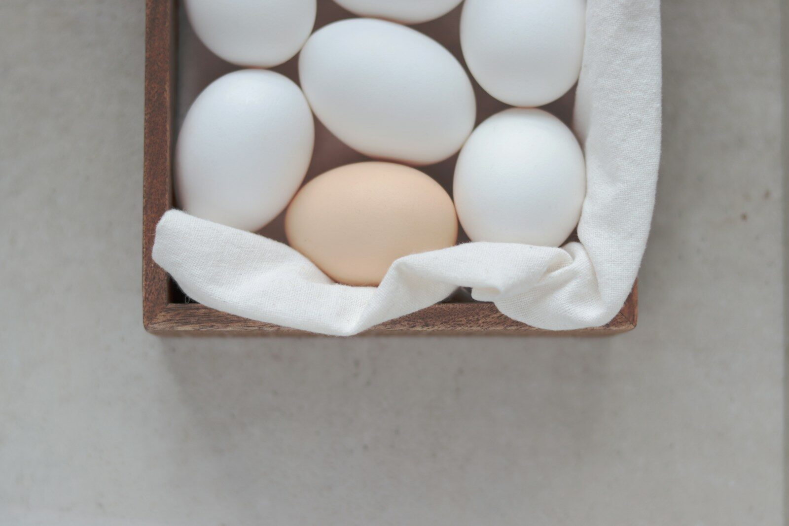 a wooden box filled with white eggs on top of a table
