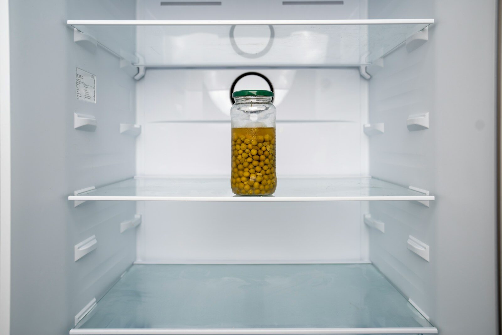 An open refrigerator with a jar of mustard in it